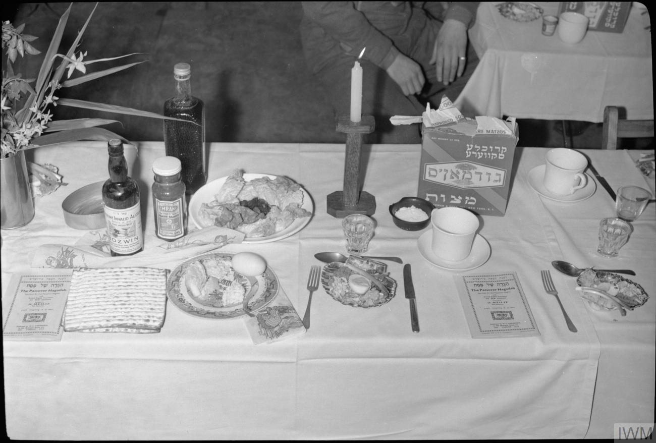 A Passover seder table set with matzah, haggadahs, and a seder plate, photographed in the 1940s