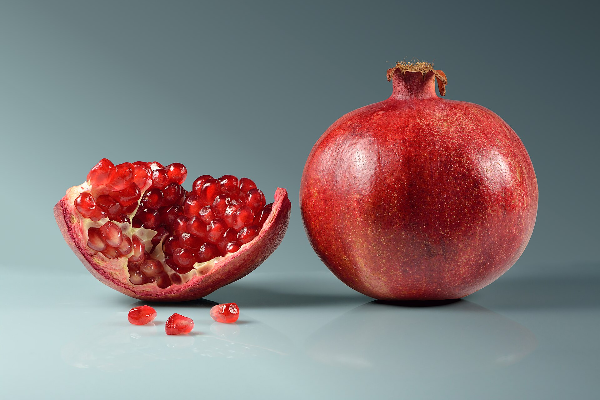 Whole pomegranate and cut open pomegranate with visible arils, showing the fruit's seeds used as a symbolic food for Rosh Hashanah