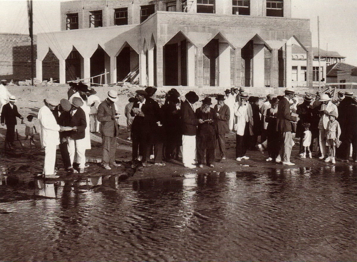 A Tashlich prayer gathering by the shore in Tel Aviv, worshippers holding prayer books at the water's edge, 1920s
