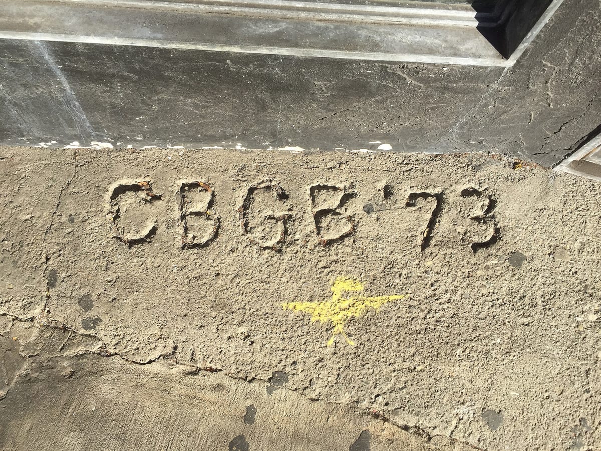 Old sidewalk graffiti reading "CBGB '73" carved into the concrete outside the club's former Bowery location