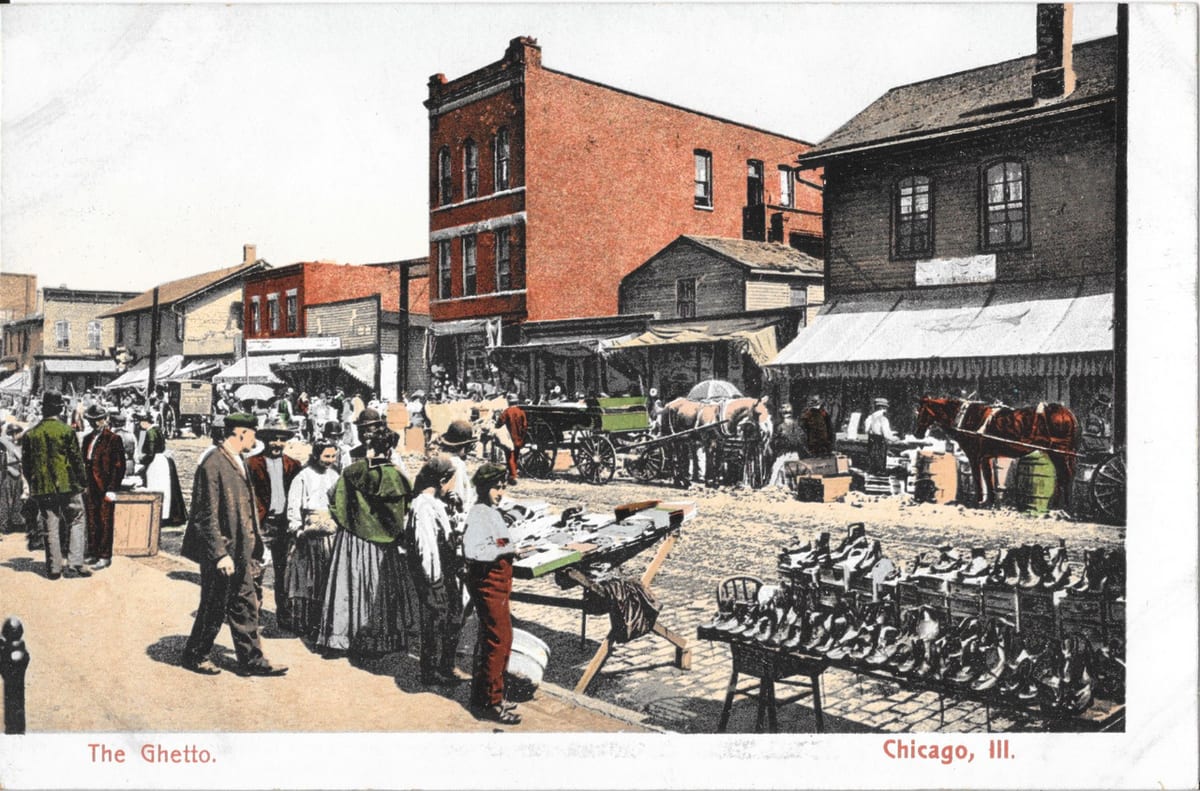 Postcard titled "The Ghetto," showing a crowded Maxwell Street market scene with horse-drawn wagons, shoppers, and merchandise laid out on tables, circa 1910